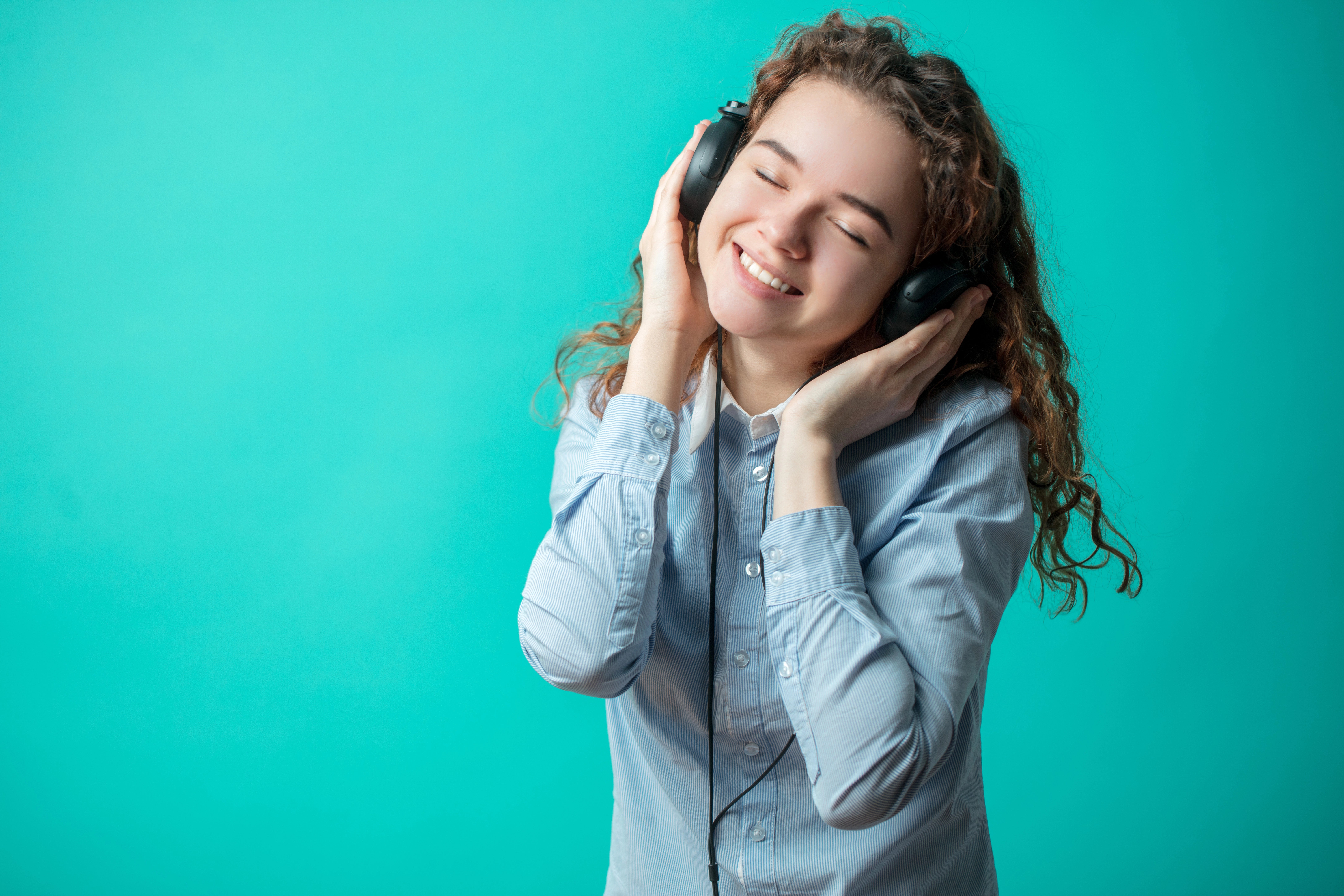 A person wearing headphones and laughingDescription automatically generated
